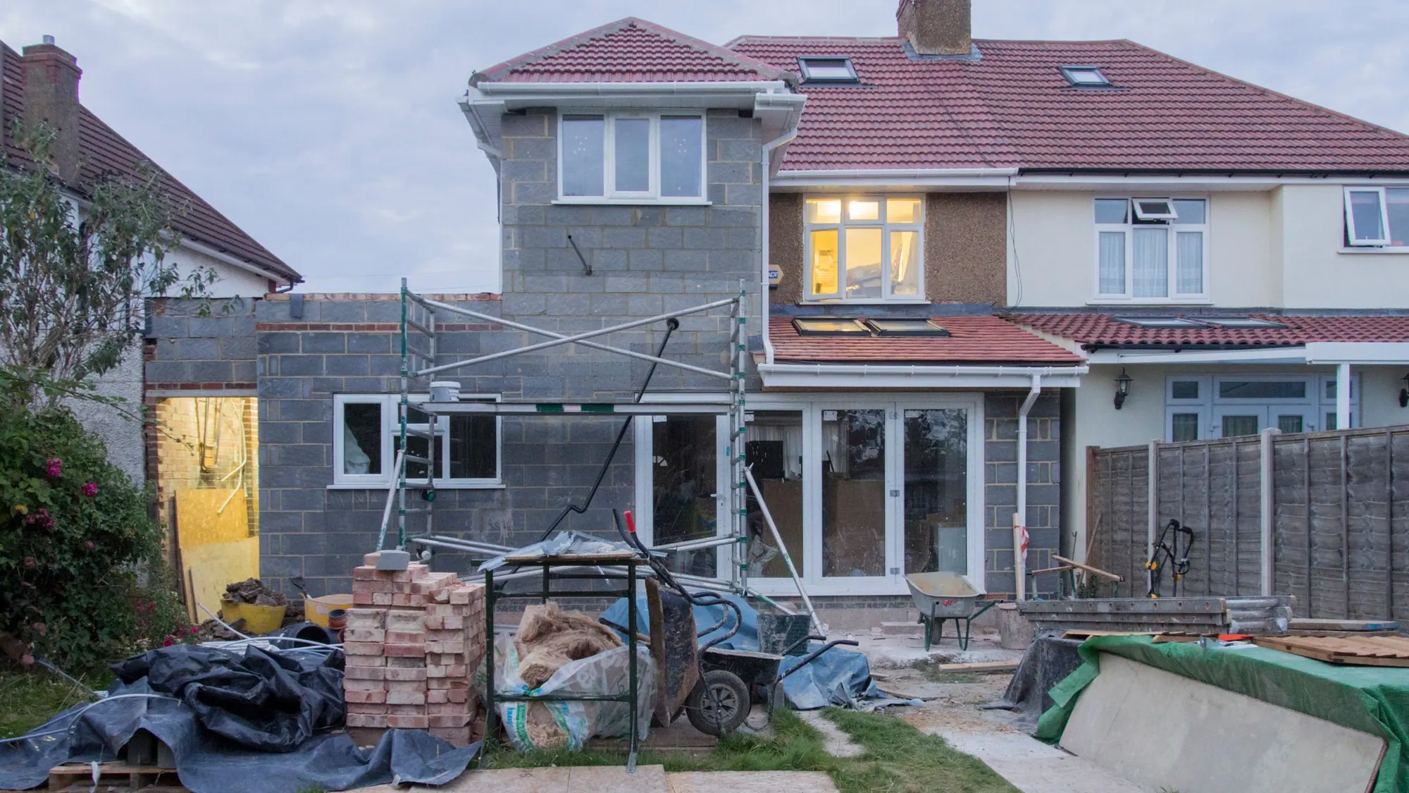 A rear extension under construction on a UK semi-detached house, blockwork up to first-floor level